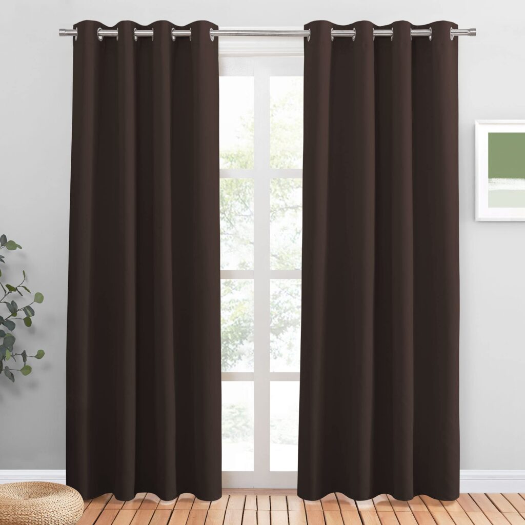 Modern interior with dark brown curtains, leafy view, plant, and minimalist artwork.